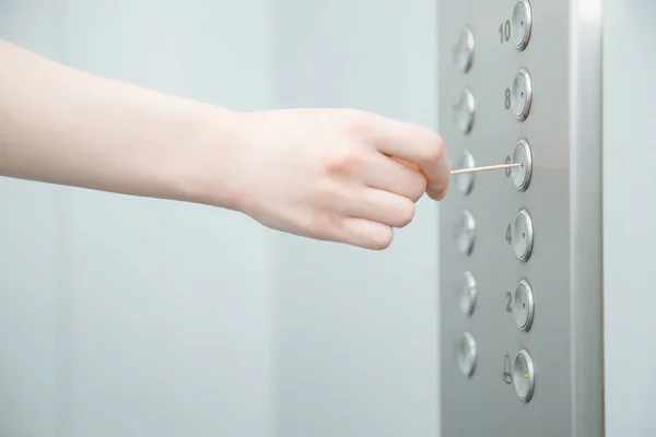 Woman hand presses elevator button with sweep. Concept coronavirus disinfection