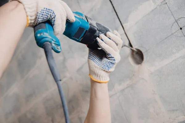 Constructor hombre con perforador de martillo neumático con corona de diamante haciendo agujero en la pared para cable eléctrico, zócalo, interruptor — Foto de Stock