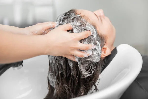 Hermosa mujer morena recibiendo lavado de pelo en el salón de belleza —  Fotos de Stock