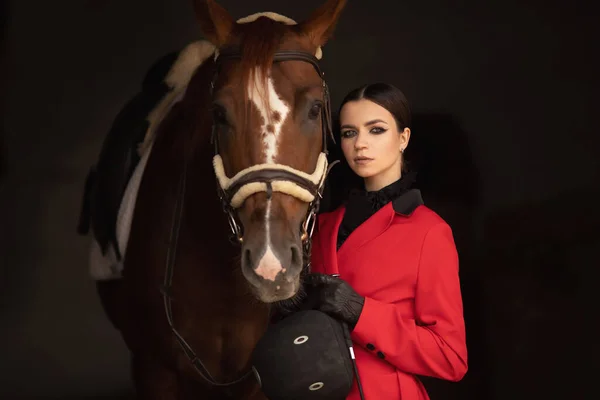 Cavalier jockey femme câlins avec cheval brun, fond noir — Photo