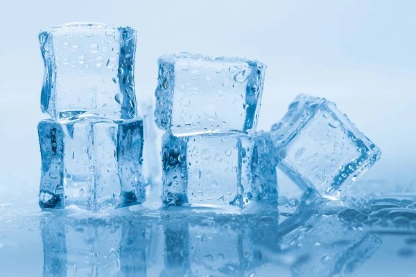 Cubos de hielo cuadrados con gotas de agua limpia sobre fondo azul —  Fotos de Stock
