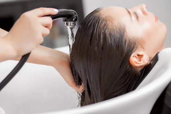 Schamponerande hår i spa skönhetssalong av ung brunett kvinna, frisör vårda klient — Stockfoto