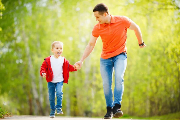 Father and son run in hand on road in summer park. Happy family concept