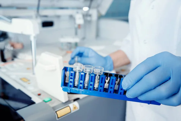 Bioengineer tiene tubos de ensayo de muestras de sangre para el análisis de ADN y presencia de virus en el citoplasma, fondo borroso — Foto de Stock