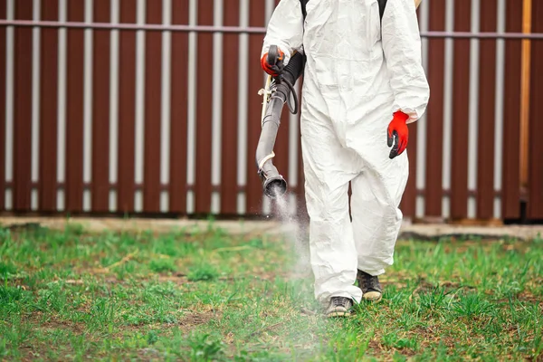 Koruyucu giysilerdeki dezenfektanlar bahçe arazisindeki işlemler. Sivrisinek, kene ve böceklerden zehir püskürtüyor.