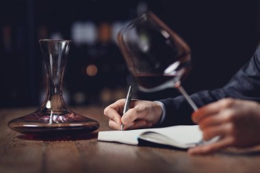 Sommeliers erkeği kırmızı şarabı tadıyor ve aroma degukasyonu kartı yazıyor.