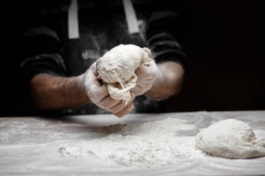 El fırıncısı hamur mayasını siyah arka planda beyaz toz unuyla hazırlıyor. Makarna ve pizza için kepçe.