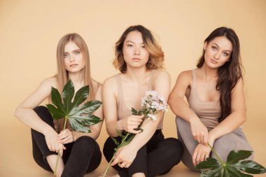 Mutlu arkadaşlar, doğal yeşil yapraklı çok kültürlü kadınlar, açık tenli sarışın manken kız. Moda florası güzelliği kavramı