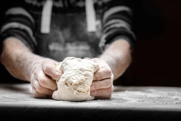 Kéz pék készítés élesztő tészta fehér por liszt fekete alapon, kanál tészta és pizza — Stock Fotó