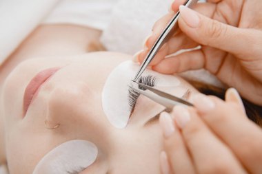 Kirpik uzatma prosedürünü kabul et. Makro fotoğrafçı kadın güzellik salonunda uzun kirpikleri var.