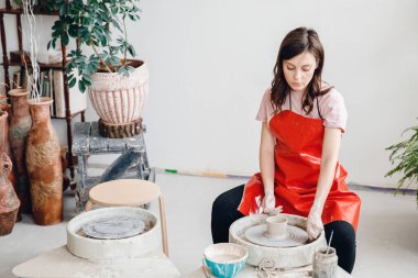 Sanatçı zanaatı, iş yerinde konsantrasyon. Güzel çömlekçi kız fırında kavrulmak için çömlek yapıyor.