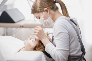 Kadın efendi sahte kirpik uzatma prosedürü yapıyor.