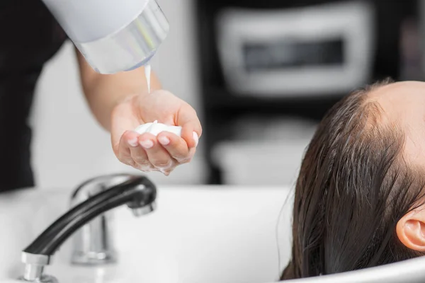 Frisör applicerar schampo och hårbalsam klienthuvud. Begreppet spa skönhetssalong — Stockfoto