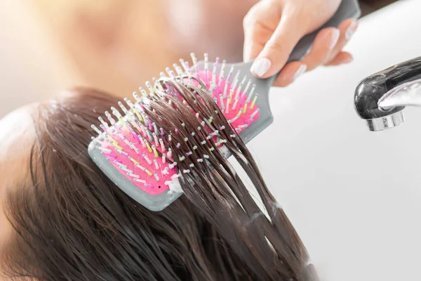 Master aplica acondicionador al cabello usando peine de masaje. Champú con limpieza profunda especial en el salón de belleza — Foto de Stock