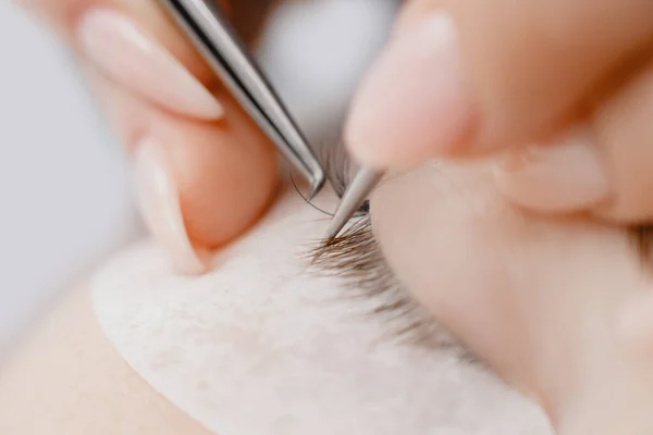 Foto macro Procedimento de extensão da pestana. Mestre pinças falsos longos cílios belos olhos femininos — Fotografia de Stock