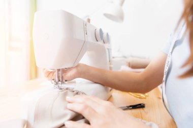 Dikiş işlemine yakın çekim, terzinin elleri kumaşı tutuyor