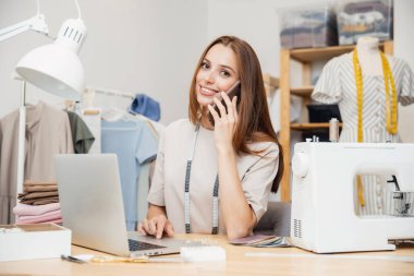 Çevrimiçi terziden, moda tasarımcısından, terziden sipariş veriyorum. Genç bayan telefonu tutuyor ve gülümsüyor.