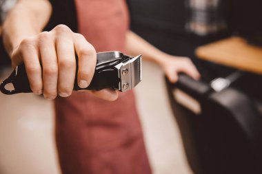 Berber modern berber dükkanında erkekler için saç makası tutuyor, kahverengi retro.