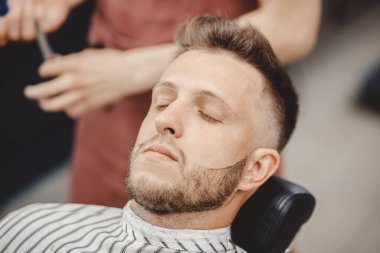 Berber dükkanında tıraş olurken jilet sakallı hippi.