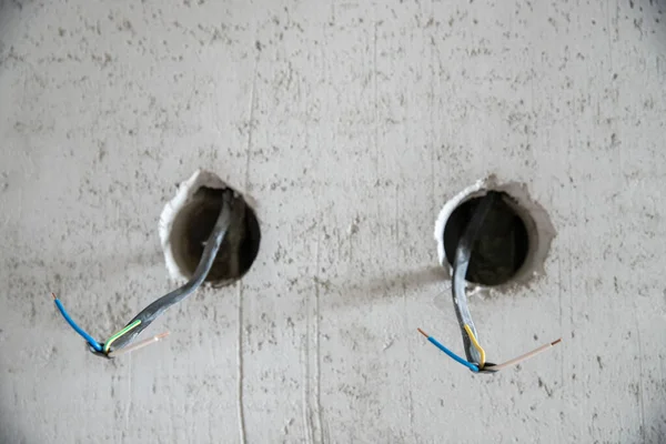 전기 기술자는 대충 마무리하는 전기 작업을 하여 아파트 배출구를 위한 구리 전선을 연결하고 마운트 한다 — 스톡 사진