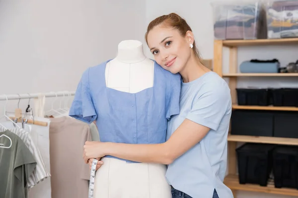 Alfaiate pinos, bela jovem mulher sorri e trabalha com manequim para produção e costura de roupas na moda — Fotografia de Stock