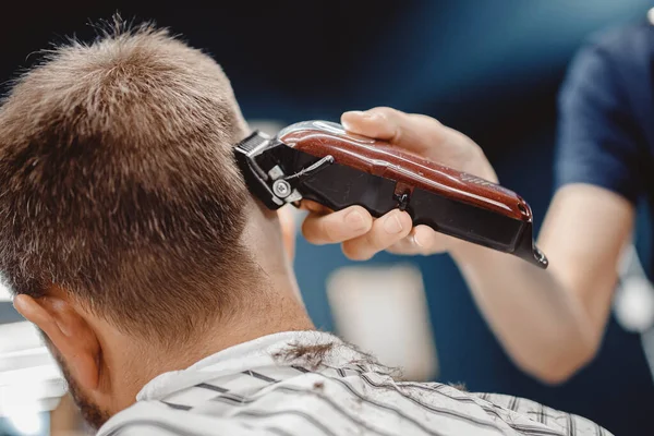 Kapper in kapperszaak scheren haar elektrisch naar jonge man voor modieuze kapsel — Stockfoto