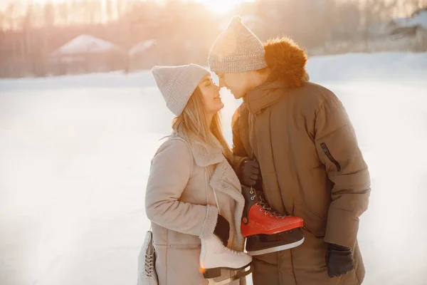 Vacaciones de Navidad, hombre joven y hermosa chica sostienen patines para pista de hielo en invierno, pareja amante — Foto de Stock