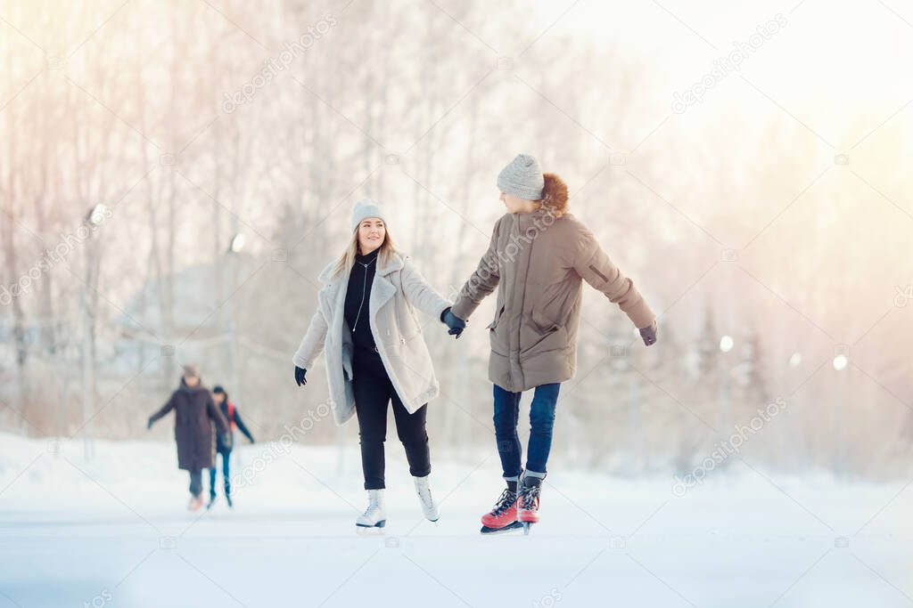 Happy young couple in sunny winter nature ice skating
