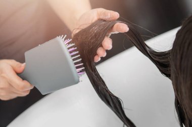 Genç esmer bir kadının güzellik salonunda saçlarını şampuanlayıp müşteriyle ilgilenen kuaför.