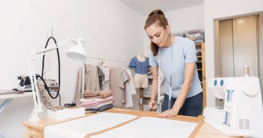 Terzi, makas desenli elbise detaylarını dikiş makinesi için taslak çizgilerinde keser. Terzinin işyeri