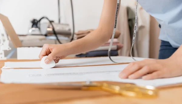 Женщина швея делает шаблон с мелом на ткани для шитья одежды в портной студии — стоковое фото