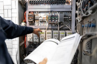 İşçi mühendisi elektrikçi ölçümlerini endüstriyel üretim için çoklu ölçer ile kontrol ediyor