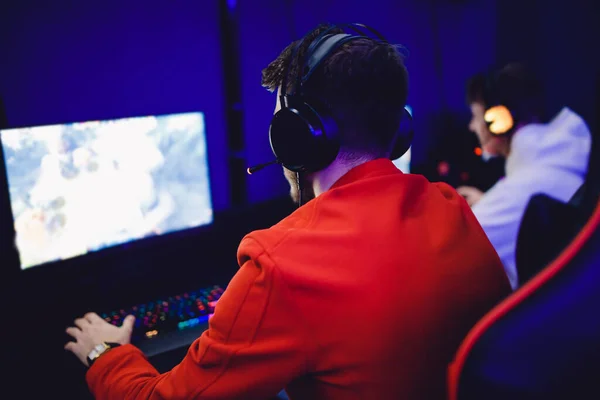 Amigos chicos jóvenes juegan videojuegos en línea con auriculares en un café club de Internet. Concepto de equipo de Esports — Foto de Stock