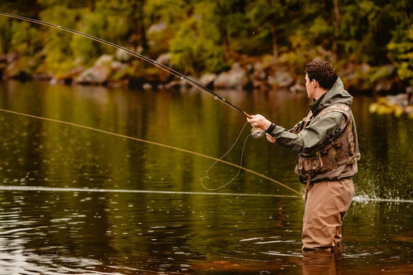 Pescador con caña pesca con mosca en río de montaña — Foto de Stock