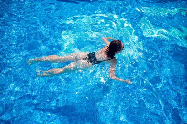 Woman black swimsuit swimming on blue water pool hotel, top view — Stock Photo, Image