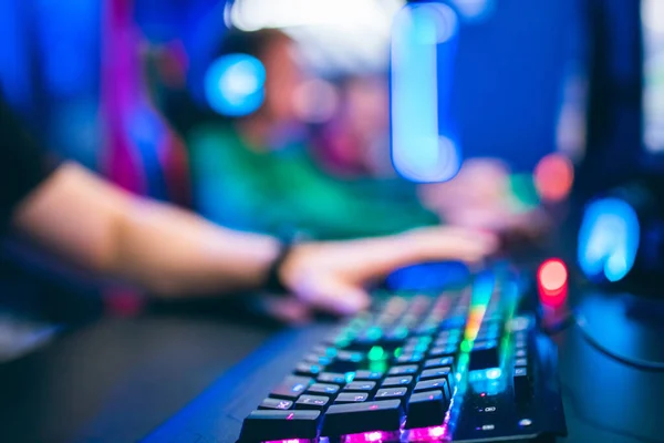 Niewyraźne tło profesjonalny gracz grający w turnieje gry online komputer ze słuchawkami, czerwony i niebieski — Zdjęcie stockowe