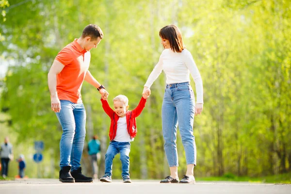 Feliz família caucasiana pais e menino no parque ao ar livre, luz solar. De mãos dadas — Fotografia de Stock
