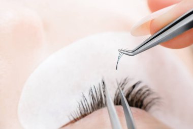 Kirpik uzatma prosedürünü kabul et. Makro fotoğrafçı kadın güzellik salonunda uzun kirpikleri var.
