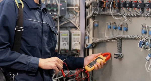 Ingegnere operaio controlla le misure dell'elettricista con tester multimetro per la produzione industriale — Foto Stock