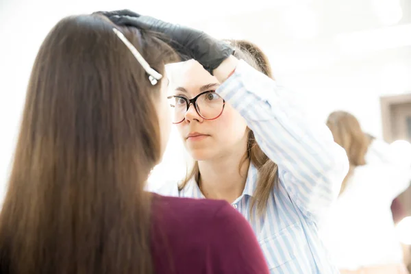 Correction and tinting eyebrows, master applies thread to woman on brow