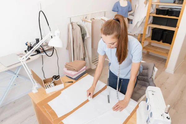 トップ表示女性のシームレスは、テーラーメイドのスタジオで服を縫製するための生地にチョークでパターンを作る — ストック写真