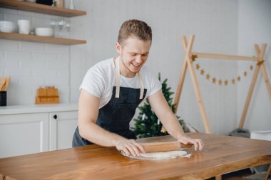 Genç Avrupalı şef mutfak arka planında hamur için merdane tutuyor. Çevrimiçi ana sınıf video hazırlayıcı kavramını kabul et