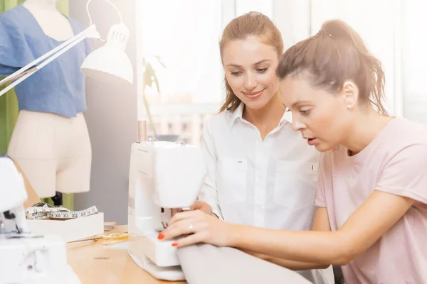 若い女性は自動機械を縫製服の糸でマスタークラスで個々のレッスンを行います。コンセプトビジネス縫製ファッションとデザイン — ストック写真