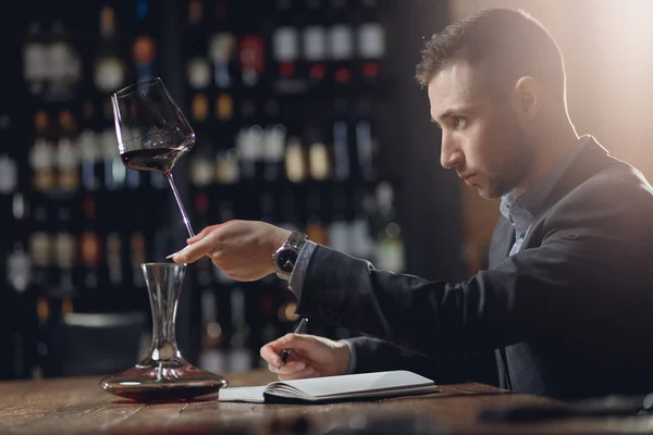 Sommeliers macho degustação de vinho tinto e fazer notas aroma cartão degustação — Fotografia de Stock
