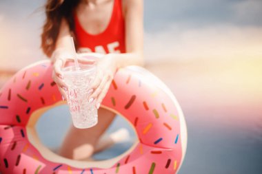 Kumsalda dinlenme ve rahatlama kavramı. Bardakta kokteyl tutan genç bir kadın, kırmızı mayo fotokopi odası.