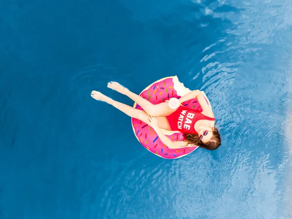 Aerial top view Young woman swimming on inflatable pink donut in transparent blue sea — Stock Photo, Image