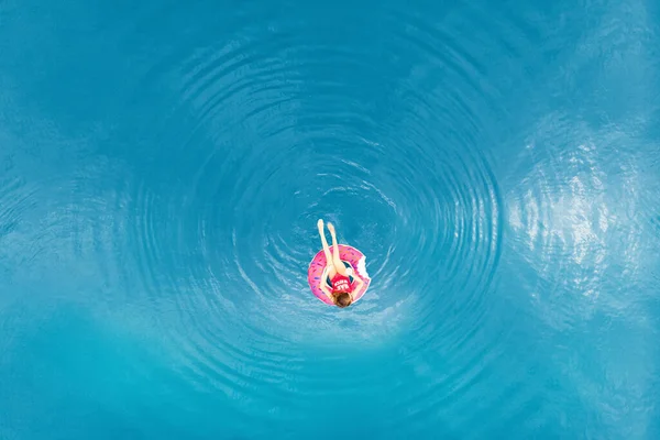 Молодая женщина плавает на надувном круге пончика в прозрачном голубом море. Вид сверху с воздуха, отдых бирюзовая вода — стоковое фото