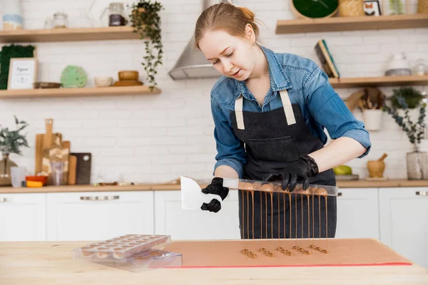 Ζαχαροπλάστης ετοιμάζει γλυκά καραμέλες από βελγική σοκολάτα στο φόντο της κουζίνας. Μικρή έννοια σπίτι των επιχειρήσεων — Φωτογραφία Αρχείου