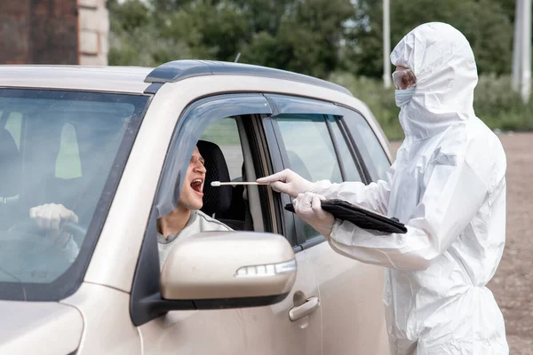 Γιατρός με προστατευτική στολή ιού που παίρνει μάκτρο από τον οδηγό προσώπου για να εξετάσει για λοίμωξη από τον ιό του στομίου COVID-19 — Φωτογραφία Αρχείου