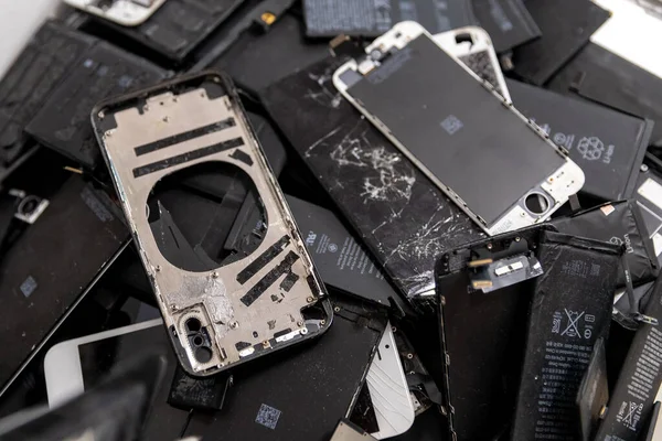 Pantallas de teléfonos iPhone Apple rotas y baterías recargables usadas en el taller de reparación de reciclaje, RUSIA - 27 de julio de 2020 — Foto de Stock